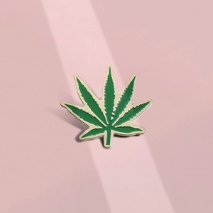 Broche créative en émail feuille de plante verte avec bordure dorée sur fond épuré
