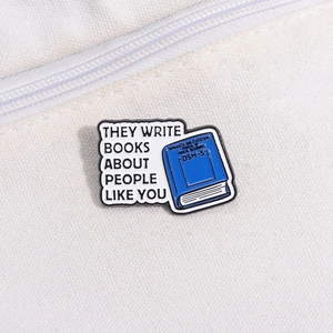 Enamel book brooch with They Write Books About People Like You quote and DSM-5 design
