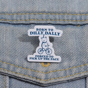 Detailed enamel pin featuring a bear riding a bike on blue denim fabric background