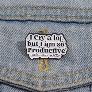 Detail einer kunstvollen Emaille-Anstecknadel mit Spruch auf einer Jeans-Tasche