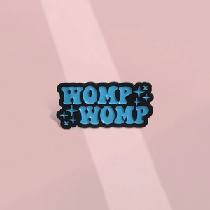 Épingle en émail avec texte WOMP WOMP bleu clair et étoiles sur métal noir