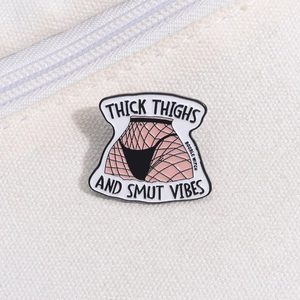 Detail of enamel pin with Thick Thighs text on beige canvas background