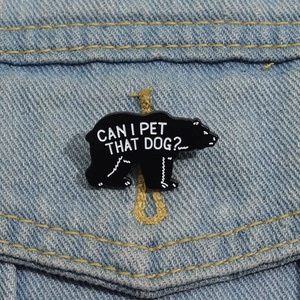 Cute black enamel bear brooch with 'CAN I PET THAT DOG?' text on denim fabric