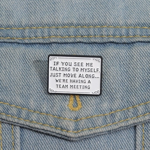 Detail of square white enamel pin with funny quote on a blue denim jacket pocket