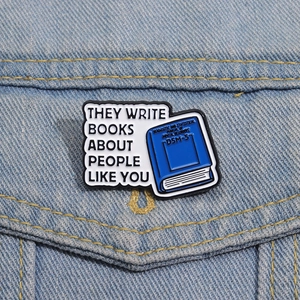 Detalle del pin esmaltado de libro azul colocado en el bolsillo de una chaqueta