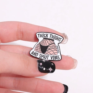 Macro detail of enamel pin featuring thick thighs artwork and black letter typography
