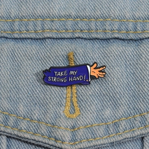 Broche en émail amusante 'Take My Strong Hand' sur poche de veste en jean
