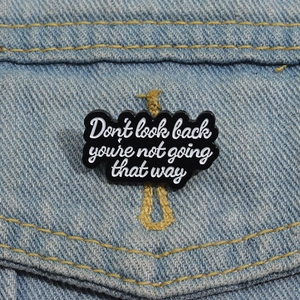 Broche en émail noir sur veste en jean avec texte Don't look back you're not going that way