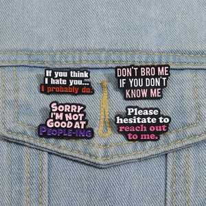 Lot de quatre pin's émaillés humoristiques avec slogans sur fond de veste en jean bleue