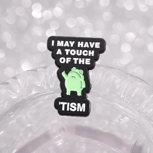 Funny green frog enamel pin with I May Have A Touch Of The Tism text on glass
