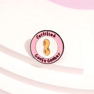 Pink circular enamel pin with peanut design and Certified Goofy Goober lettering