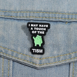 Green frog enamel pin on denim with text I MAY HAVE A TOUCH OF THE 'TISM