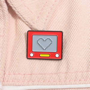 Macro shot of red retro console enamel pin with pixel heart on pink denim fabric