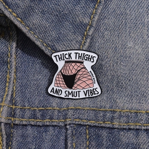 Macro shot of an enamel brooch with fishnet pattern and text on blue denim fabric