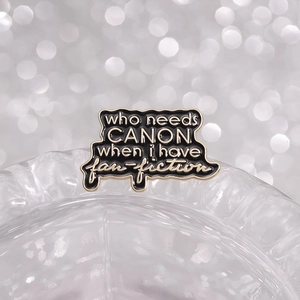 Black and gold enamel pin with Who Needs Canon When I Have Fanfiction text on glass
