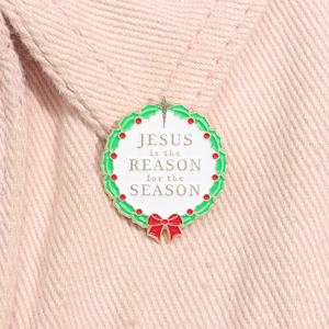 Macro shot of wreath enamel pin with Jesus is the Reason text on pink denim fabric