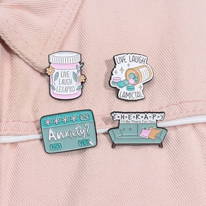 Detailed view of four mental health enamel pins on pink denim fabric, showing fine texture