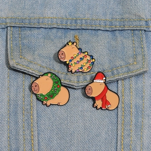Close-up of three Christmas Capybara enamel pins on a blue denim jacket pocket