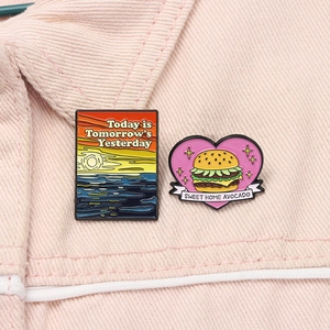 Detail of enamel badges with sunset landscape and avocado burger on pink fabric