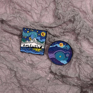 Artistic enamel pins featuring Van Gogh starry sky and Hobbit hole landscape on purple background