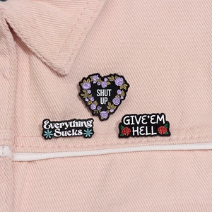 Detailed close-up of three enamel pins with slogans pinned on a pink denim jacket