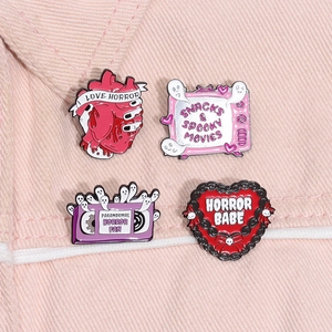 Detail of four retro horror enamel pins featuring heart and TV icons on pink denim fabric