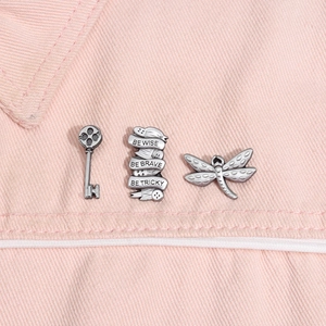 Détail de breloques libellule et clé en argent vintage sur tissu en denim rose