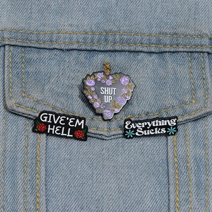 Close-up of enamel flower badges with sassy slogans pinned on a denim jacket pocket