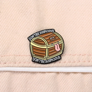 Detail of Mimic chest enamel pin with Don't Be Suspicious text on beige denim fabric