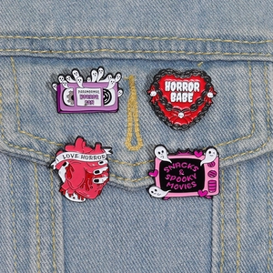 Gros plan de pins en émail thème horreur sur denim avec motifs de cœur et télévision rétro