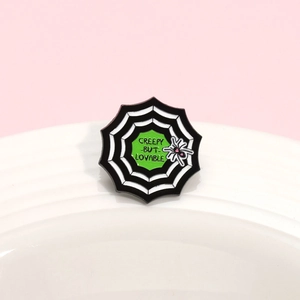 Spider web enamel pin with 'Creepy but Lovable' text and pink heart spider detail