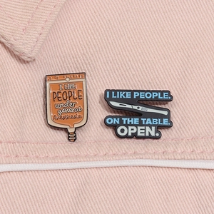 Detail of medical pins featuring IV bag and scalpel designs on pink denim fabric