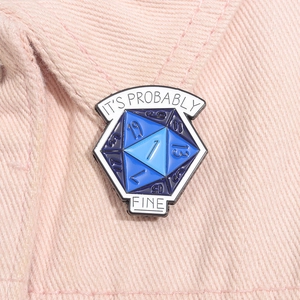 Close-up of blue D20 dice enamel pin on denim with It's Probably Fine text