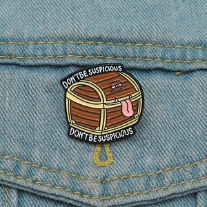 Detail of adventure game mimic chest enamel pin with slogan on denim background