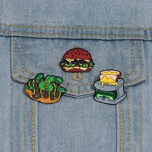 Detailed view of burger, donut, and toaster enamel pins on a denim jacket pocket