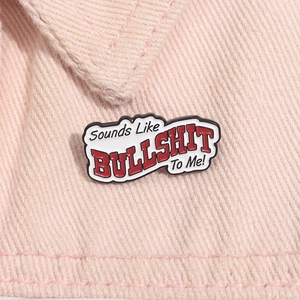 Detail of alloy brooch with Sounds Like Bullshit To Me text on pink denim fabric
