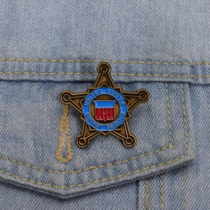 Vintage bronze pentagram secret service badge pinned on a blue denim jacket pocket