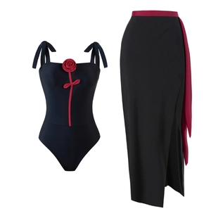 Detail of high-waisted black bikini set featuring red 3D rose and tie-side slit skirt