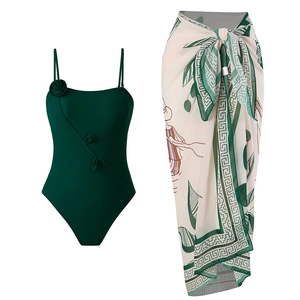 Detail of dark green one-piece swimsuit with floral 3D accent and printed wrap skirt