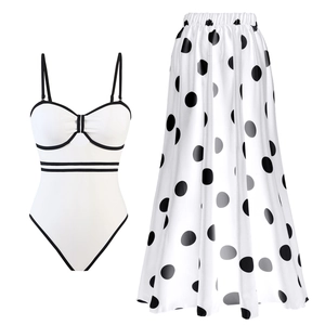 Flat lay of white one-piece swimsuit with black trim and matching polka dot chiffon skirt