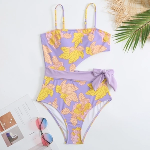 Close-up of tropical floral print swimsuit with cutout waist and bow belt detail
