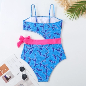 Flat lay of royal blue cutout swimsuit with pink bow and beach accessories