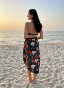 Floral print beach cover-up set with halter top and sarong skirt against sunset sea