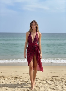 Detail of burgundy floral one-piece swimsuit with matching chiffon sarong on a beach