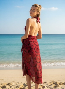 Detail of dark red chiffon beach sarong with black floral prints in seaside setting