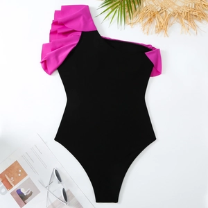 Flat lay of a one-shoulder ruffled swimsuit with black and rose pink contrast colors
