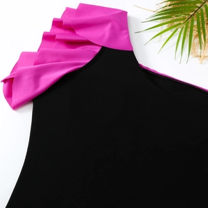 Detail of pink ruffled shoulder on black one-piece swimsuit with tropical leaf decor