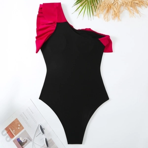 Detailed flat lay of black one-shoulder swimsuit with vibrant pink ruffled trim and accessories