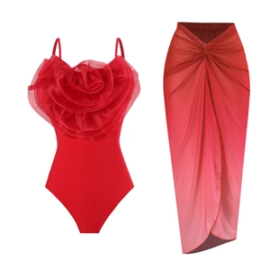 Detail of red one-piece swimsuit with 3D floral accent and gradient wrap chiffon skirt
