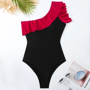 Detail of one-shoulder ruffle swimsuit with black and red contrast and holiday props